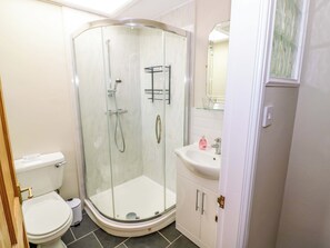 A bathroom with a glass-enclosed shower, a toilet, a sink, and a mirror. - Fern Cottage (Lichfield)