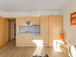 Une cuisine de taille réduite, dotée de meubles en bois, d’un four à micro-ondes et d’un lave-vaisselle.