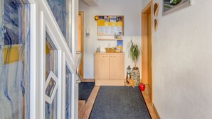 A hallway with a wooden cabinet, a bulletin board, a plant, and a red apple on the floor. - Apartment in Tyrol in an Attractive Area (Fiss)