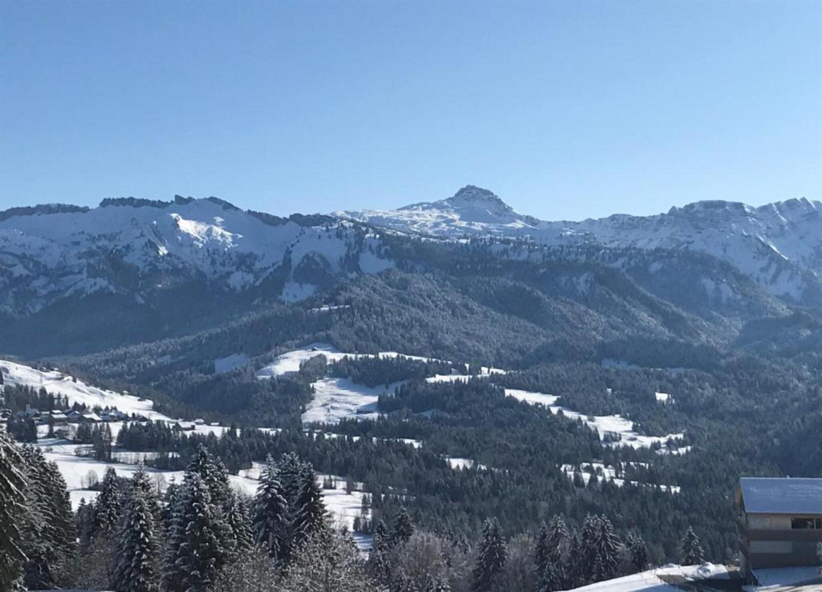 Eine gebirgige Landschaft mit schneebedeckten Gipfeln und einem kleinen Gebäude im Vordergrund.