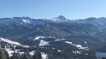 Eine gebirgige Landschaft mit schneebedeckten Gipfeln und einem kleinen Gebäude im Vordergrund.