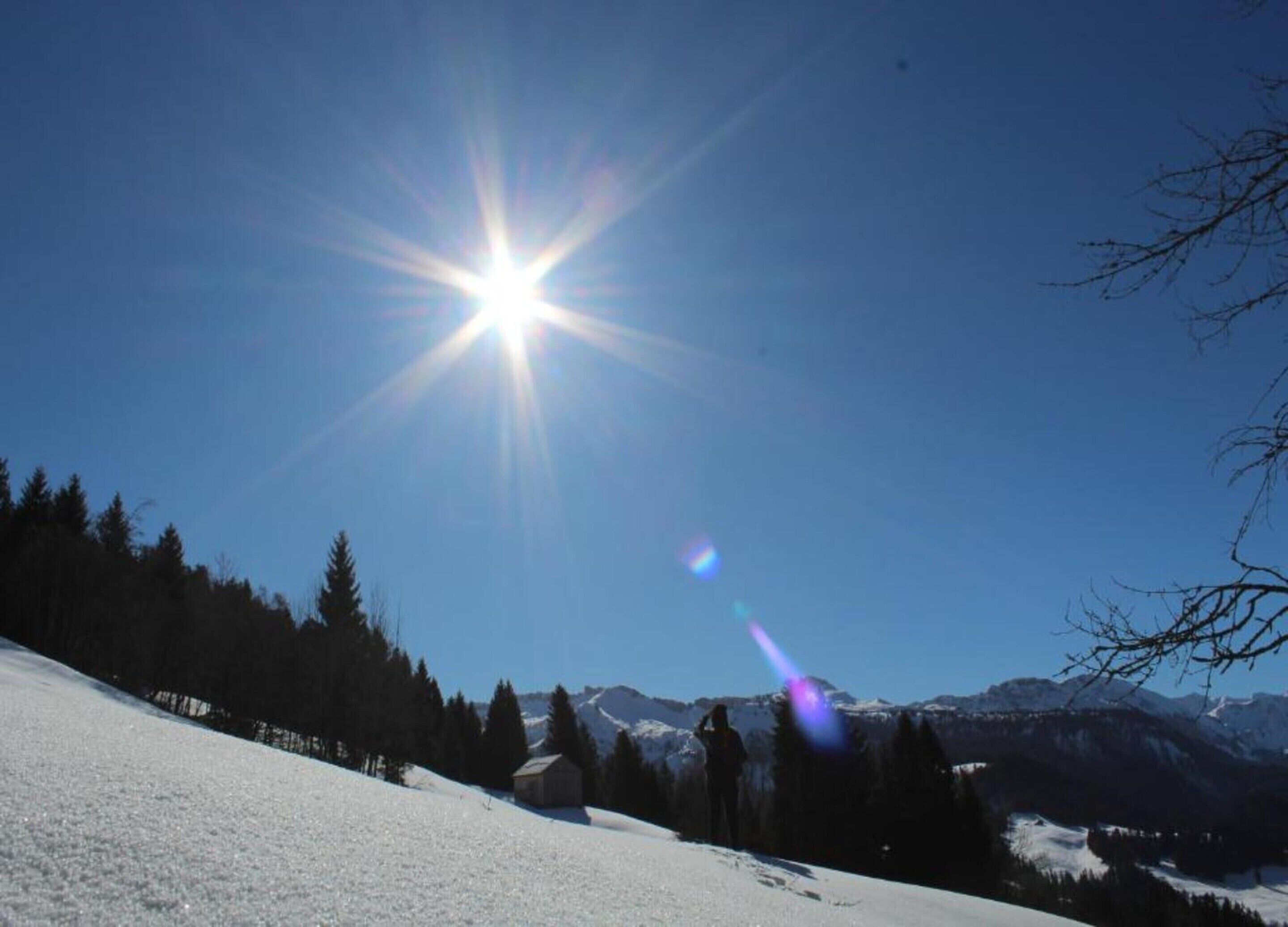 A snowy mountain landscape with a clear sky and a bright sun.