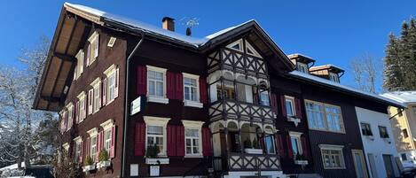 A traditional chalet with a steeply pitched roof, dormer windows, and a symmetrical facade.