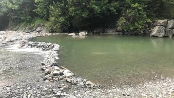 Un río de aguas transparentes, rodeado de rocas y un follaje verde denso.