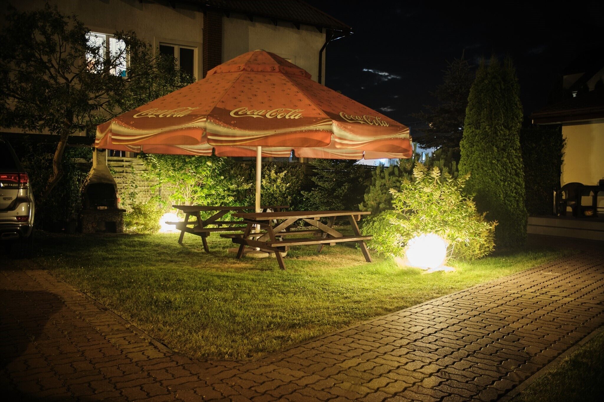 A Coca-Cola branded outdoor umbrella and picnic table at night.