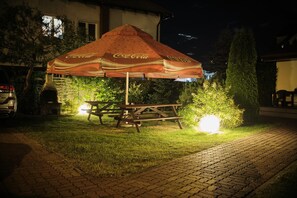 A Coca-Cola branded outdoor umbrella and picnic table at night. - Victoria Grzybowo (Grzybowo)