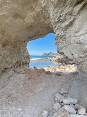 En naturlig klippformation med utsikt över en strand och havet.