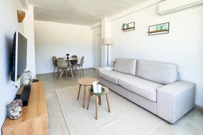 A modern living room with a sofa, TV, dining table, chairs, and decorative items. - Apartment near Arenal (Xàbia)