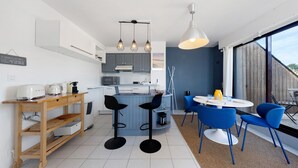 Ett modernt kök med en central köksö, barstolar, ett matbord med stolar och ett stort fönster som ger utsikt.