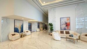 A spacious lobby with marble flooring, plush seating, and large abstract paintings. - Skyz Lifestyle 1BR Residences at Arjan (Dubai)