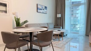A modern living room with a round table, two sofas, and a small coffee table. - Skyz Lifestyle 1BR Residences at Arjan (Dubai)