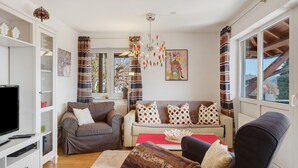 Ein Wohnzimmer mit Fernseher, Sofas, einem roten Tisch und einer Chandelüster.