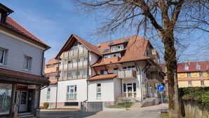 Ein mehrstöckiges Gebäude mit Balkonen, einem sichtbaren Eingang und wolkenlosem Himmel.