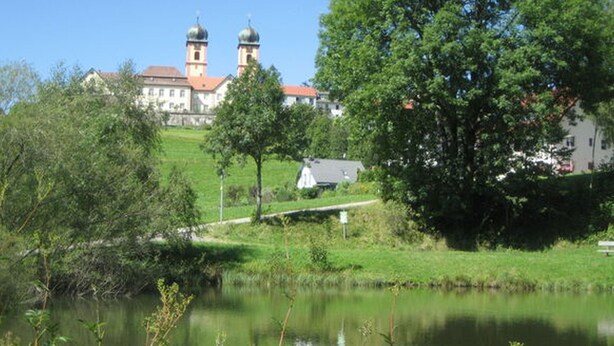 Eine friedliche Seeblick mit einer Kirche im Hintergrund, deren Turm zwei Kuppeln trägt.