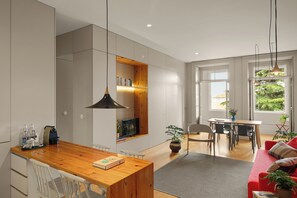Eine moderne Küche mit Holztischplatte, ein Essbereich mit Tisch und Stühlen sowie ein rotes Sofa im Wohnzimmer.