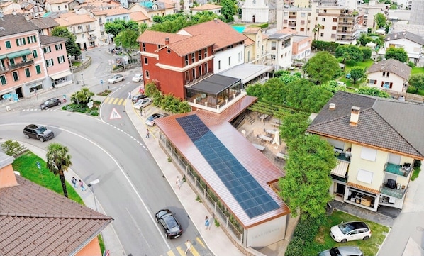 A residential area with a building featuring a solar panel roof, a pedestrian crossing, and a road with cars.