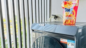 A front-loading washing machine with a detergent dispenser on top, a QR code, and a label indicating a 10-minute cycle. - SS Home Sunrise City Premium (Ho Chi Minh City)