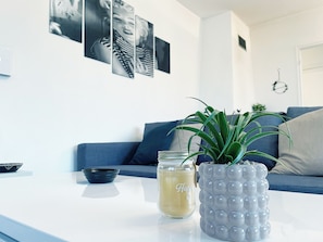 A modern living room with a blue sofa, a white coffee table, a potted plant, and a candle. - La Colridienne, cosy country house with garden, animals ok (Cauroy-lès-Hermonville)