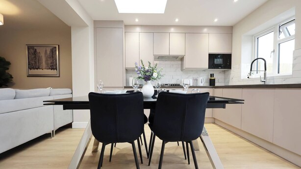 Una cocina moderna con comedor, que incluye una isla central, sillas negras y un sofá blanco.