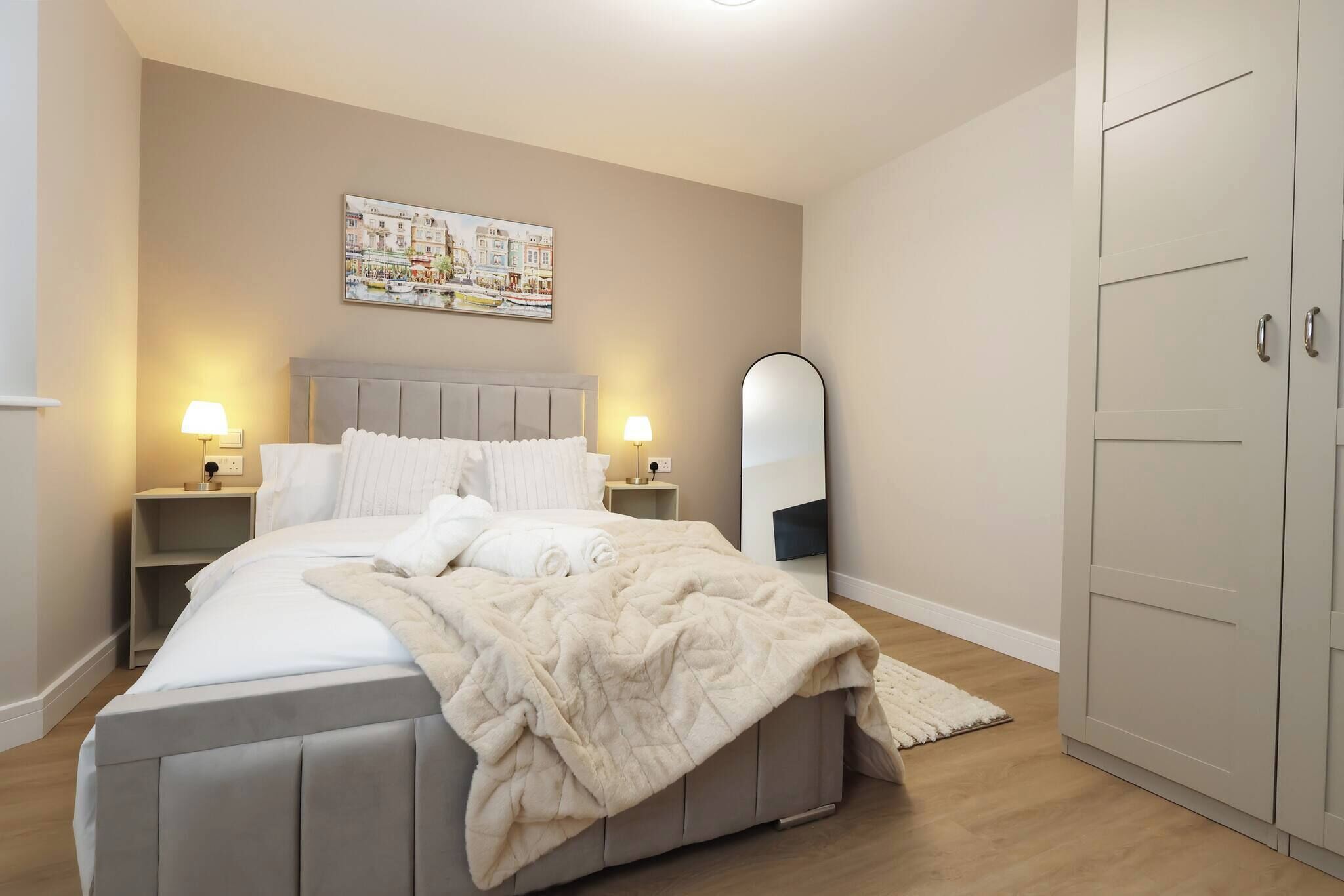 A bedroom with a bed, nightstands, a mirror, and a wardrobe.
