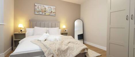 A bedroom with a bed, nightstands, a mirror, and a wardrobe.