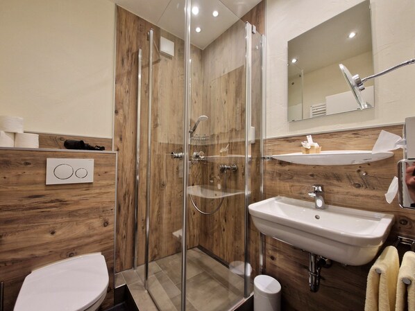 Un baño moderno con ducha envuelta en vidrio, un lavamanos y un inodoro.