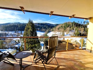 A balcony with a view of a snowy landscape and a building in the distance.