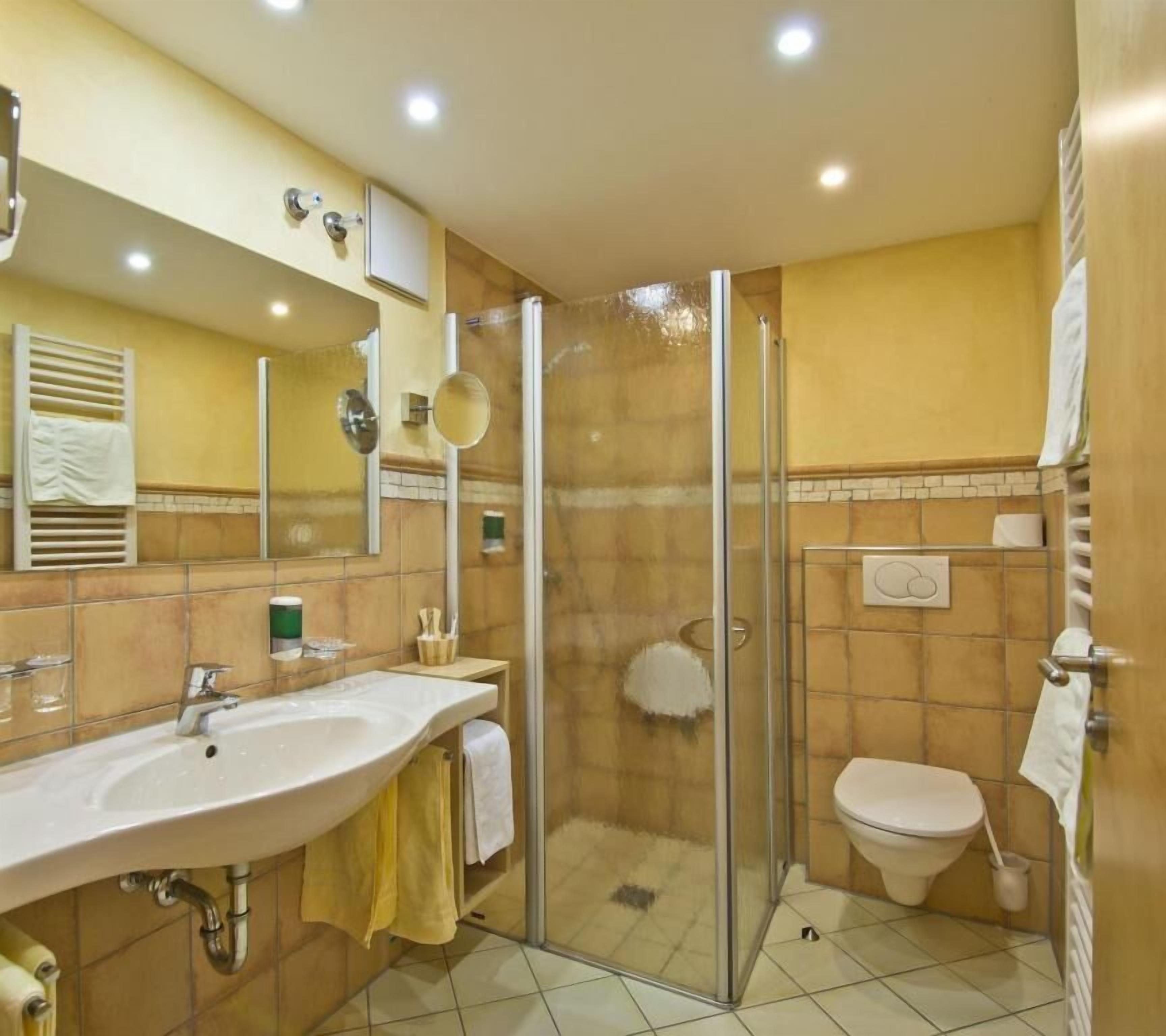 Une salle de bain moderne avec une douche à parois de verre, un lavabo avec un miroir et des toilettes.