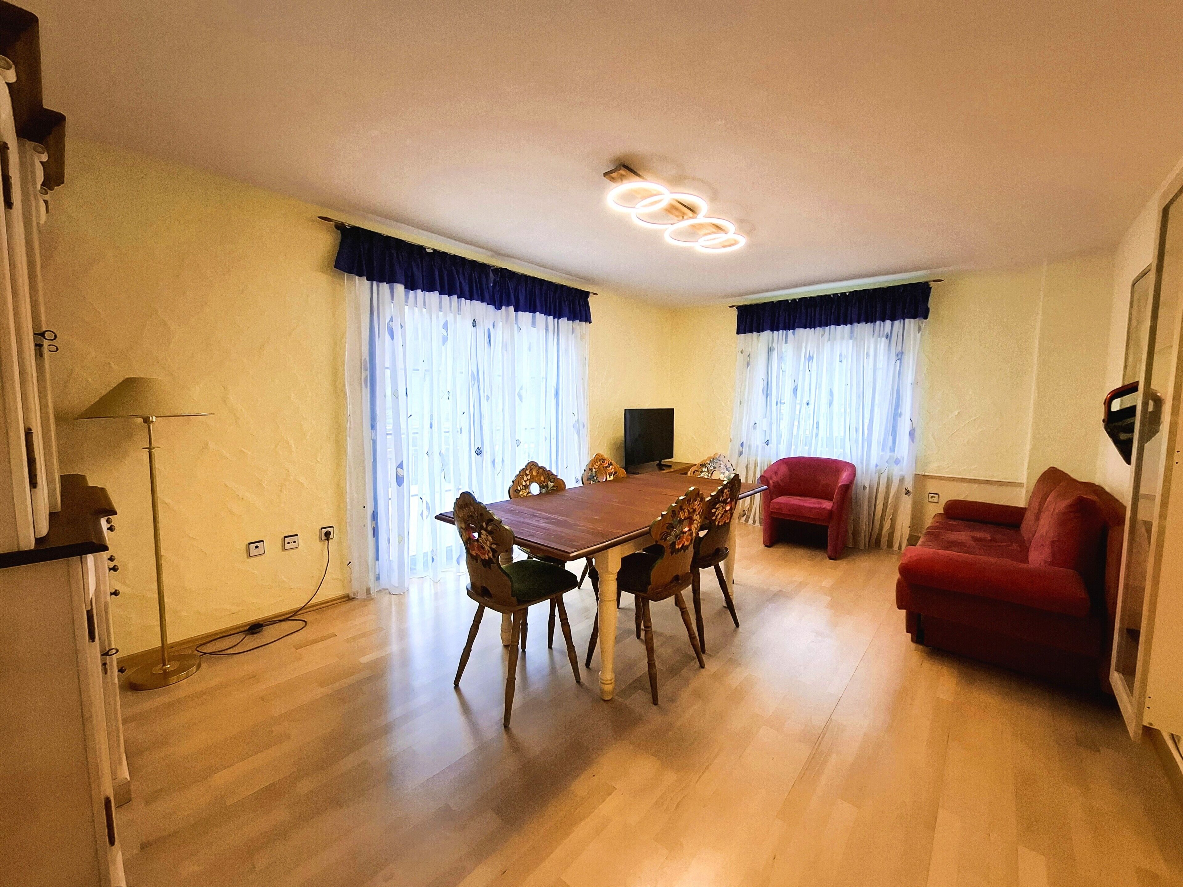 Ein Wohnzimmer mit einem Holzesstisch, einem roten Sofa und einem Fernseher.