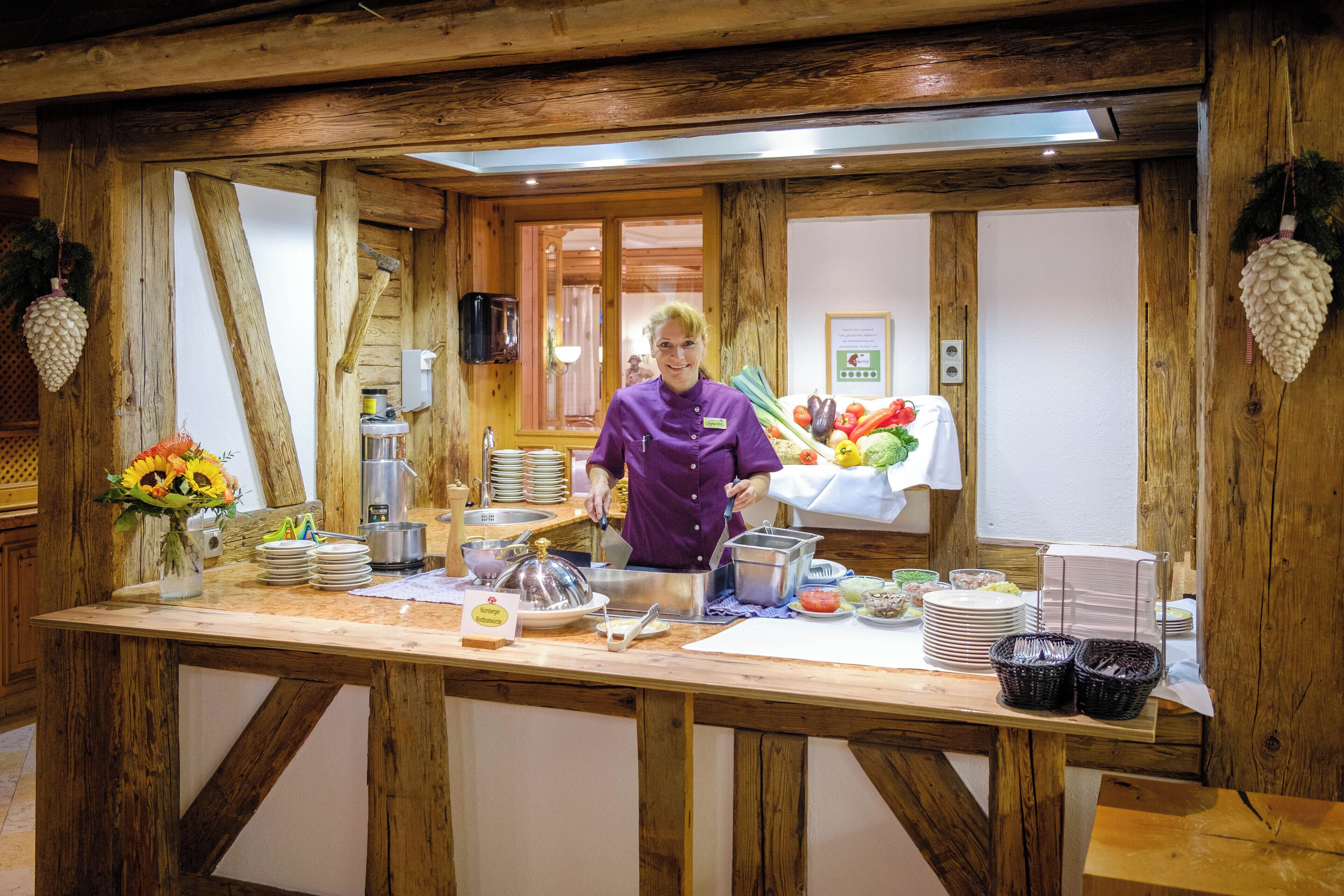 A rustic wooden buffet setup with a chef, various food items, and a wooden interior.