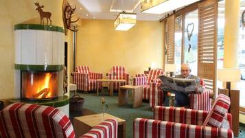 Un rincón lounge acogedor con sofás y sillones a rayas, una chimenea y un ventanal con contraventanas.