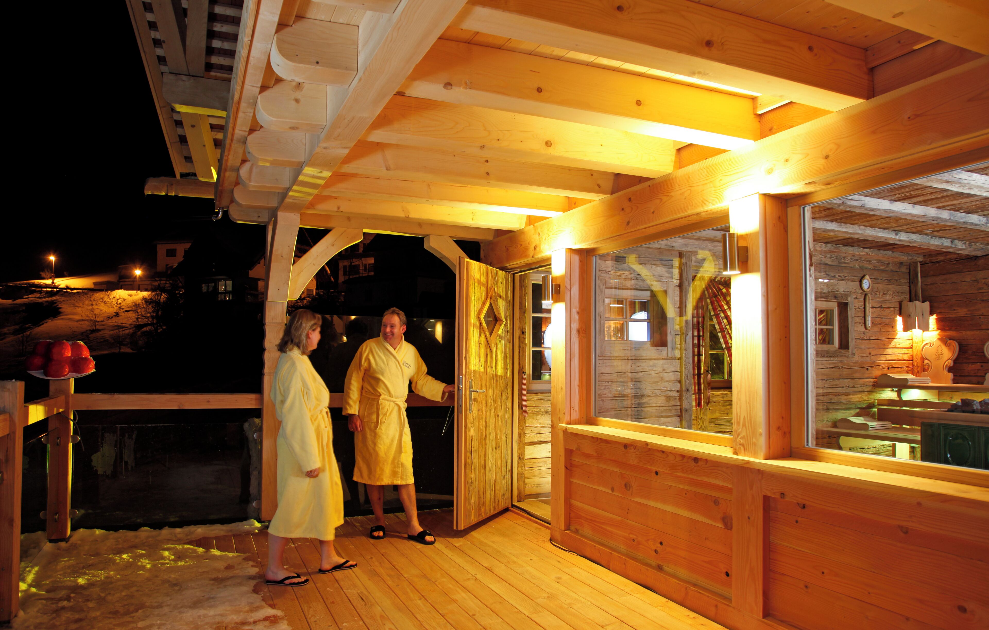 Een houten chalet met een glazen deur, een houten terras en een zwembad.