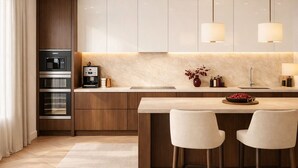 A modern kitchen with a central island, bar stools, a coffee machine, and a microwave. - Prime Covent Garden Stay - Central, Calm & Stylish (London)