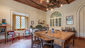 A spacious dining area with a large wooden table, several chairs, and a brick ceiling. - Apartment at Tenuta Bichi Borghesi Farm (Monteriggioni)