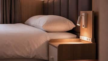 Cama bem arrumada com cabeceira, mesa de cabeceira com abajur e tomada.