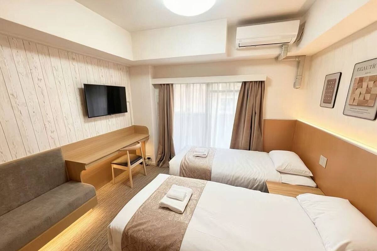 Habitación de hotel con sofá, dos camas, televisión y aire acondicionado.