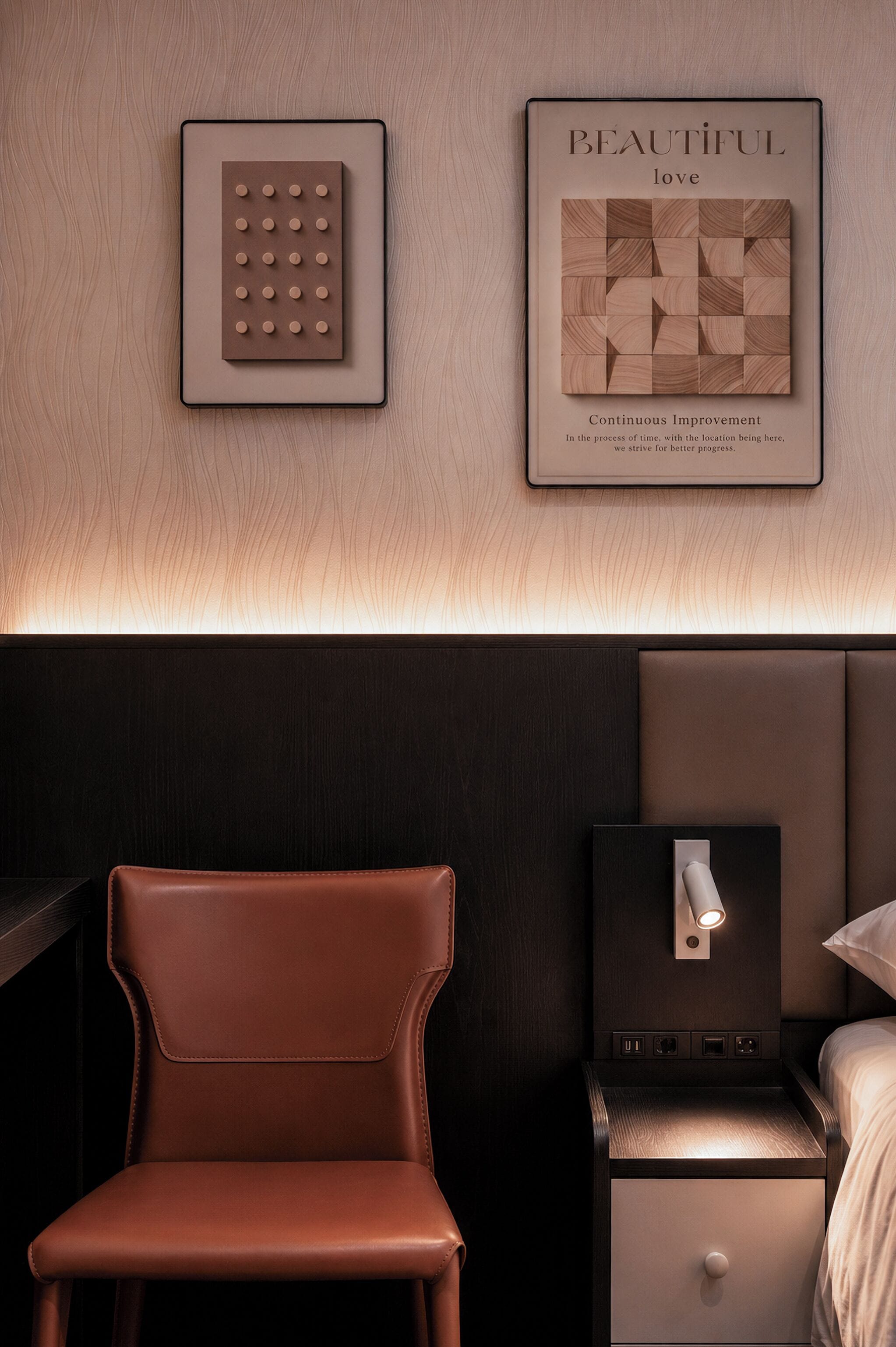 A modern bedroom with a brown leather chair, a bedside table with a lamp, and framed artwork on the wall.