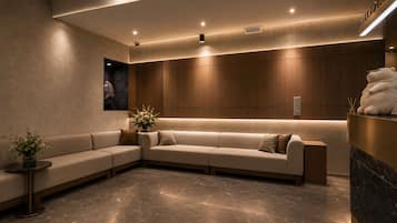 Un área de recepción moderna con un sofá modular, una mesa de recepción y un espejo montado en la pared.