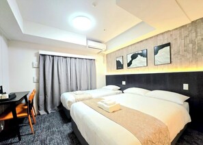 Une chambre d’hôtel avec deux lits, un bureau et une chaise.