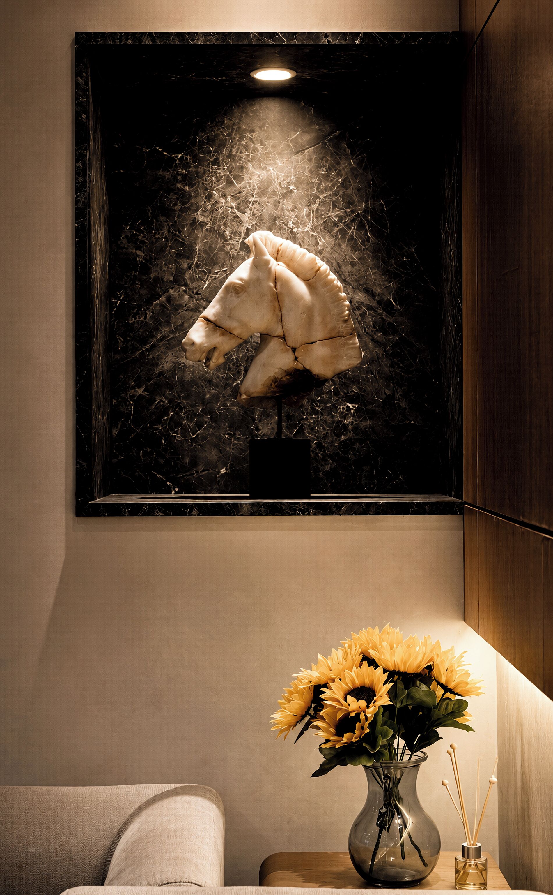 A framed sculpture of a horse's head on a wall, a vase with sunflowers, and a small table with a candle.