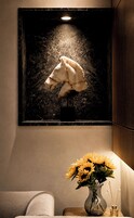 Una escultura en marco de la cabeza de un caballo en una pared, un jarrón con girasoles y una mesita con una vela.