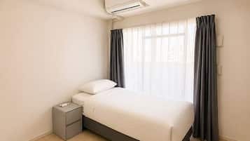 A bedroom with a bed, bedside table, and an air conditioning unit.
