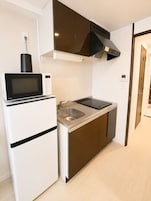 Cozinha compacta com micro-ondas integrado, pia e fogão.