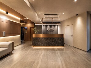 Zona de recepción de hotel con mostrador, asientos y señalización.