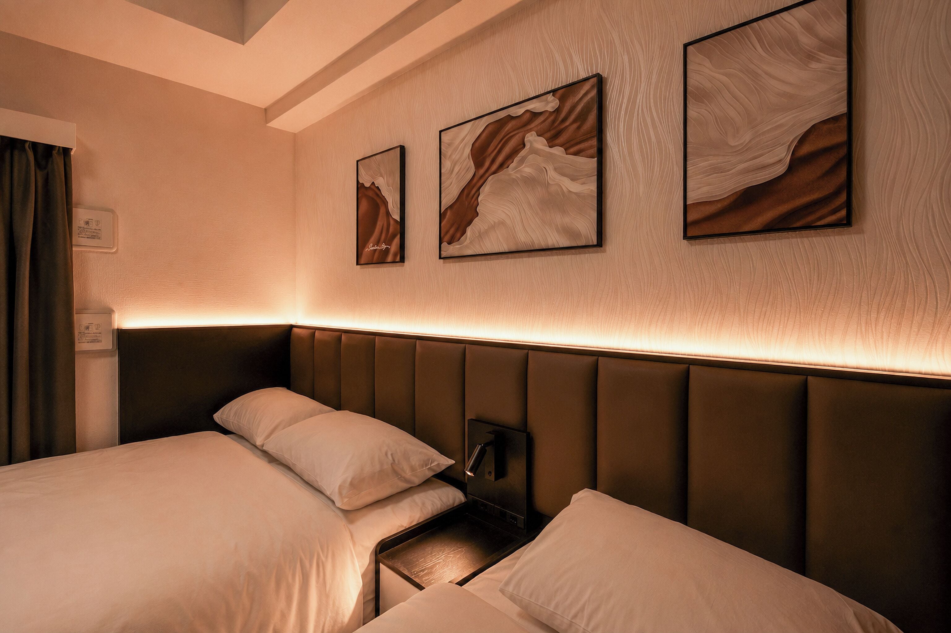 A hotel room with a bed, a nightstand, and three wall-mounted paintings.