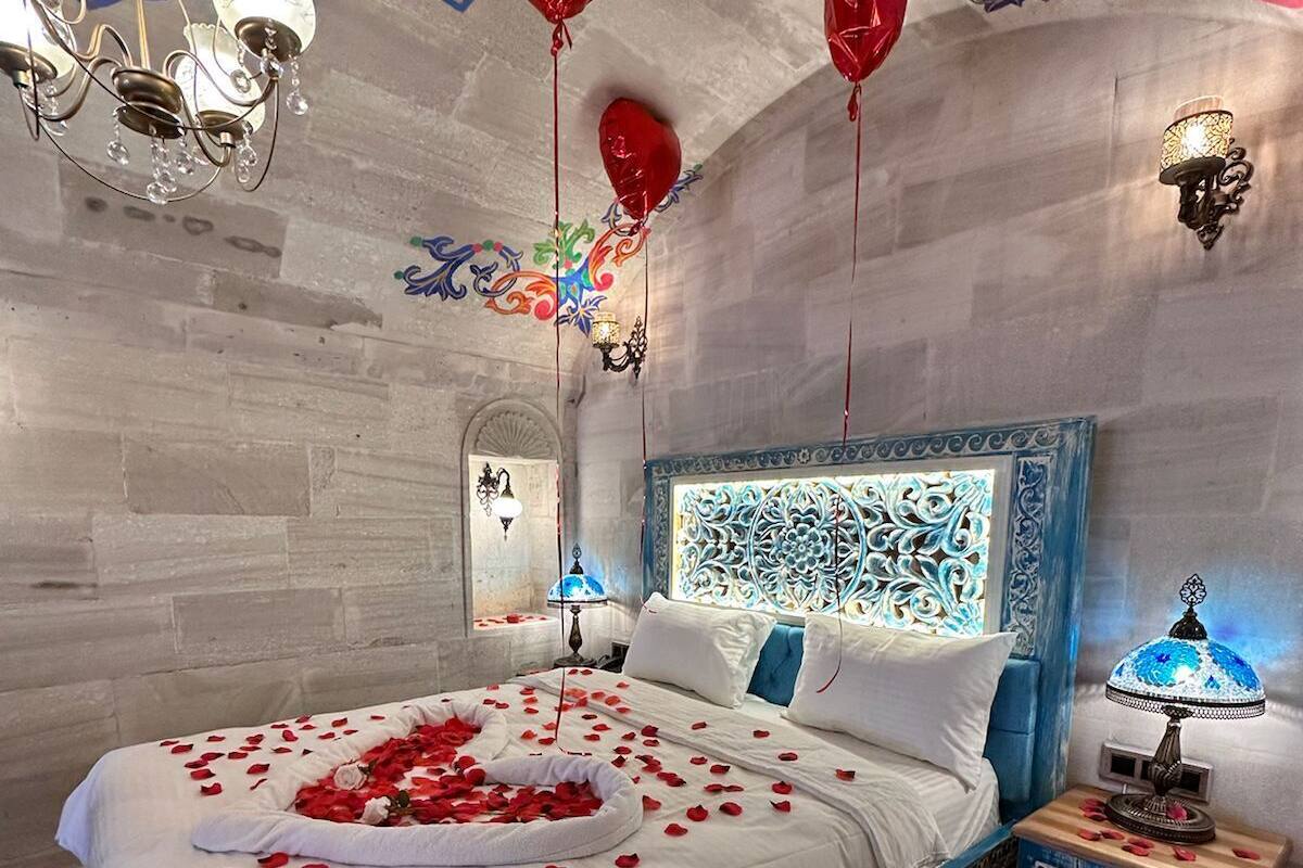 Un dormitorio con cama, un diseño decorativo en la pared y una mesita de noche con lámpara.