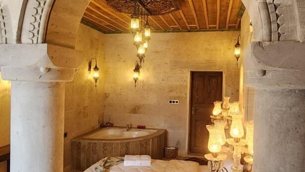 Ein Zimmer mit einem Bett, einer Holzbalkendecke, einer Steinwand und einem Steinfußboden.