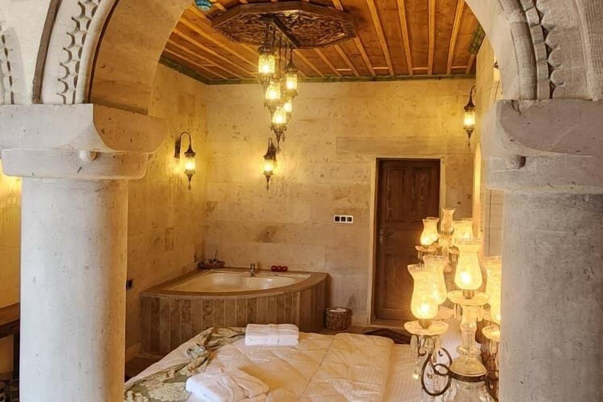 Una habitación con cama, techo de madera, pared de piedra y suelo de piedra.