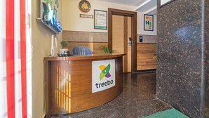 A reception desk with a 'treebo' logo, a clock, and a sign with 'HOW we roll' on the wall. - Treebo Viswa Vikas Residency (Coimbatore)