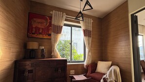 A cozy room with wooden walls, a red sofa, a wooden cabinet, and a window with curtains. - An Bang Antique Beach House (Đà Nẵng)